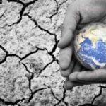 Hands holding Earth against cracked dry ground, symbolizing global water crisis and the need for Rostfrei liquid storage tank solutions